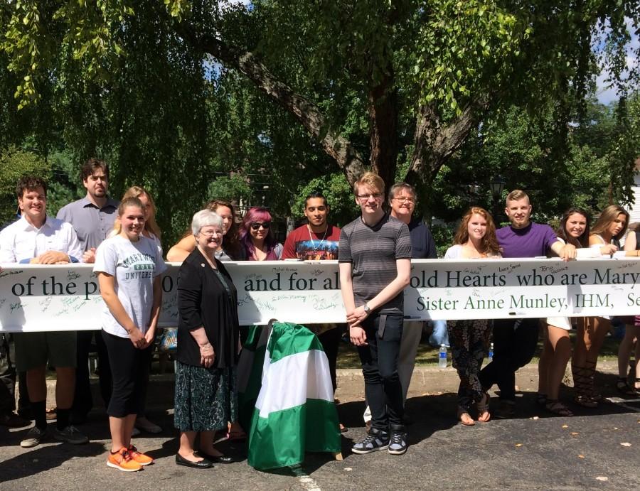 Sr. Anne Munley, I.H.M., Ph.D., proudly poses with the Marywood community in front of the last beam that will complete the frame of the Learning Commons.