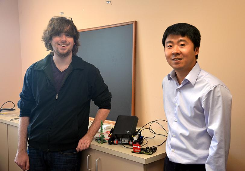 Senior Math major Travis Pitchford (left) and Computer Science professor Dr. Zaixin Lu (right) stand next to their wireless power transfer apparatus.