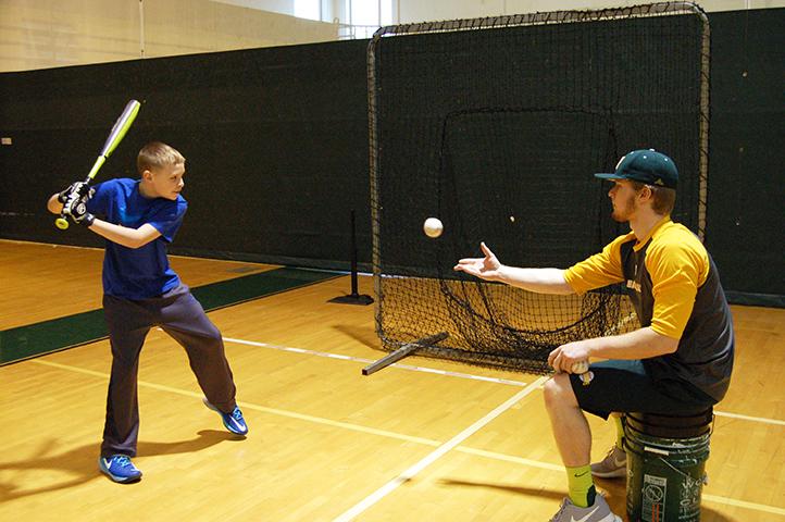 Sophomore Athletic Training major and first baseman Matt Staback tosses the ball to 6th grader AJ Keller at the Pitches In baseball clinic. 