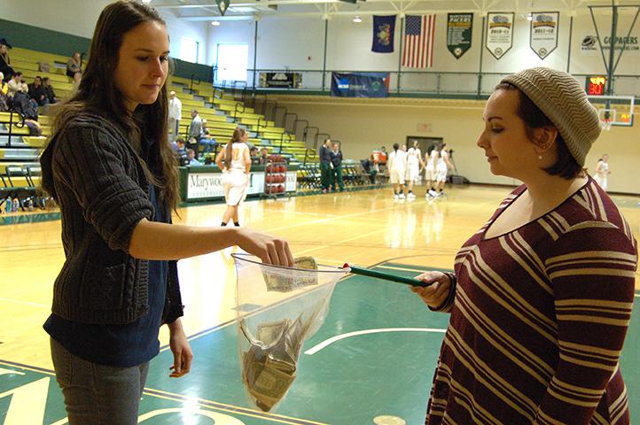 CRS member Colleen Sideck places money into fellow member Heather Keess collection that will be used to purchase malaria nets for families across the globe.