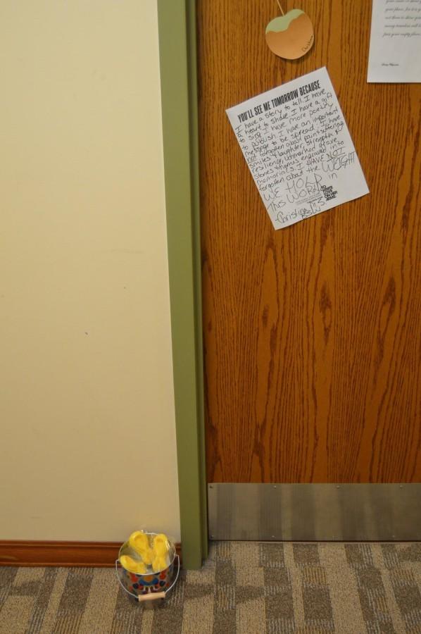 Outside of Christina's dorm door a can of lollipops and awareness signs on her door.
