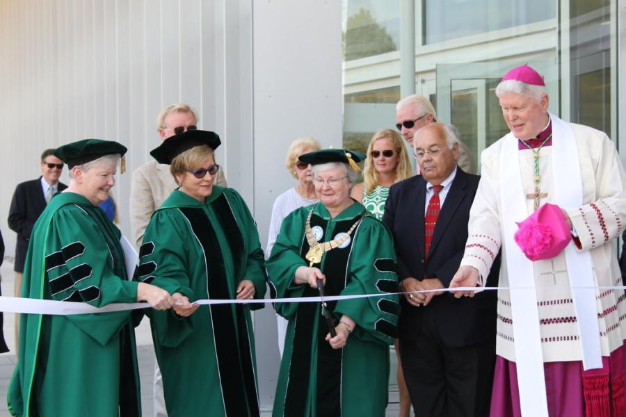 Eight members of the Presidential Party cut the white ribbon in front of an entrance into the Learning Commons.