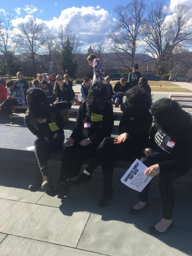 The Guerilla Girls sit in the Morgan Memorial Garden with onlookers behind. 