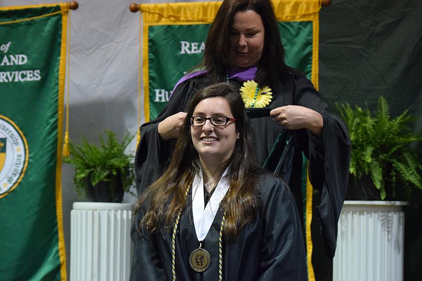 Architecture Professor Kate OConnor places a hood on graduate Elizabeth Andrzejewski at the Undergraduate Hooding and Honors Ceremony.