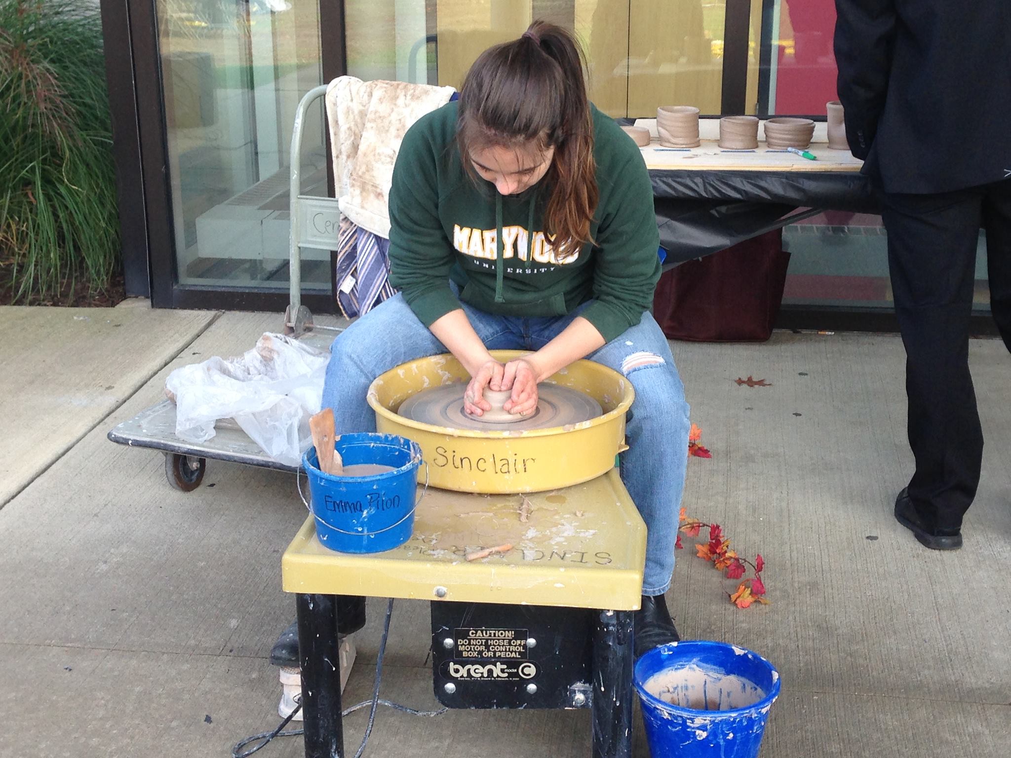 Senior ceramics/art administration major Emma Pilon does a pottery demonstration for students.