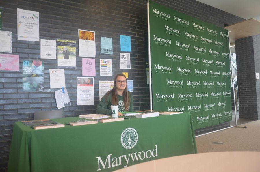 Melissa Przewlocki, graduate assistant for The Office of University Advancement and graduate student in higher education and administration, assists with the Giving Day table in the Learning Commons.