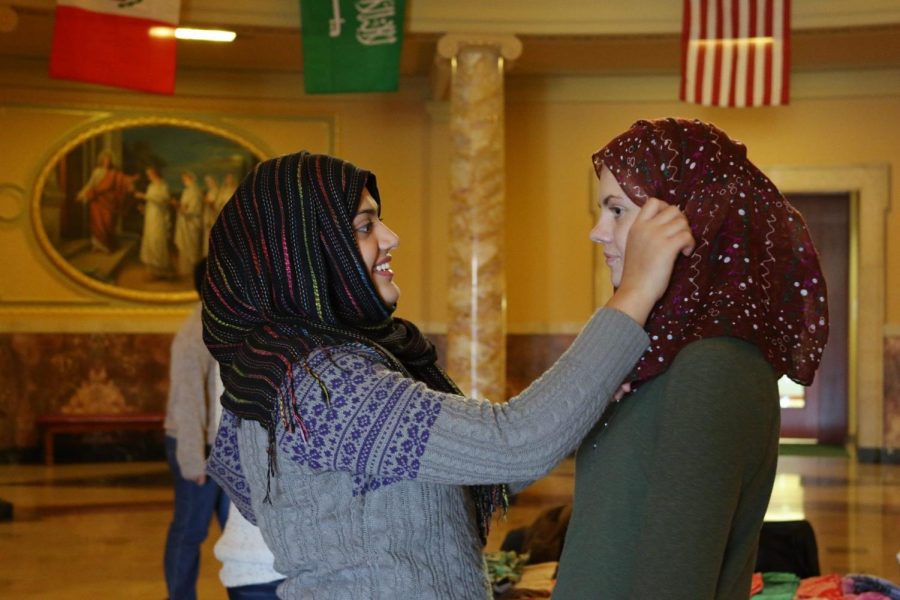 Organizer Salma Ahmed, left, shows a student how to put on a hijab.